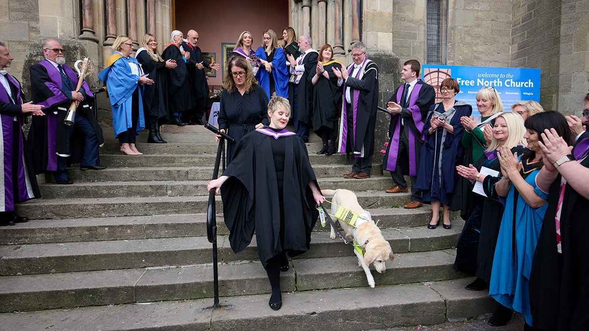 Emily Gray and her guide dog walking down steps