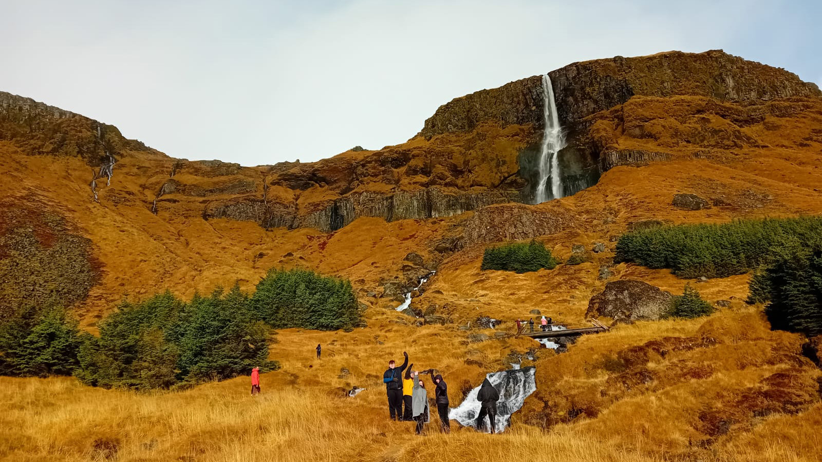 People standing at the base of a waterfall