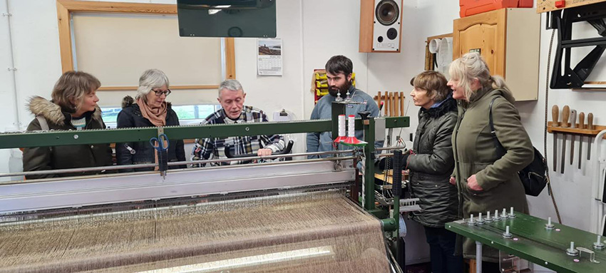 Students with a harris tweed weaver