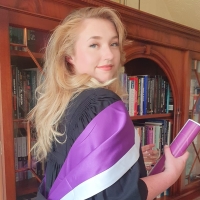 Philpppa Barnwell in graduation gown and holding her scroll