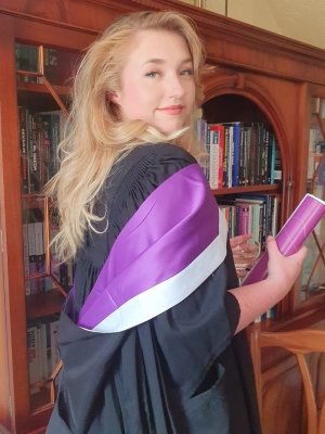 Philpppa Barnwell in graduation gown and holding her scroll