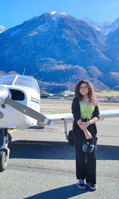 Erica Lo Presti standing in front of a small plane, with mountains behind