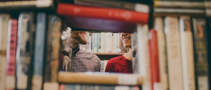 Two people smiling behind a row of books