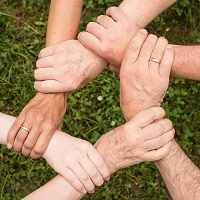 Six people linking hand to wrist in a circle