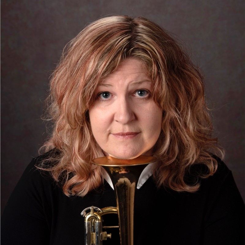 Pauline sitting with a musical instrument propped under their chin