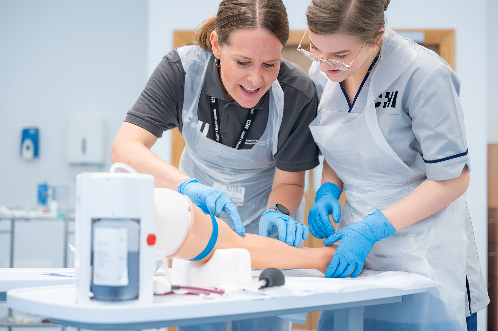 Nurses practicing taking blood on a dummy arm