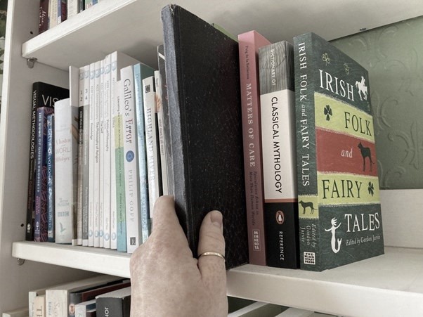 Person pulling a book off a shelf