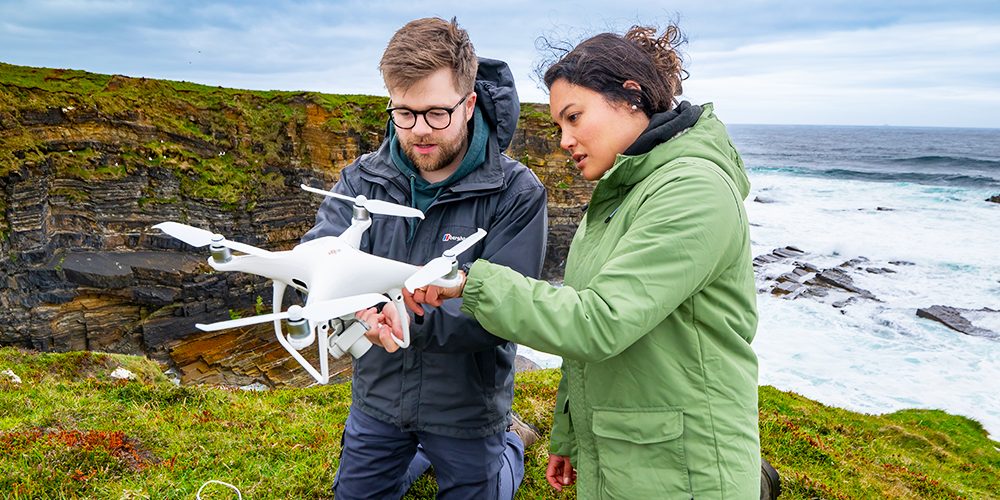 Two researchers examining a drone.
