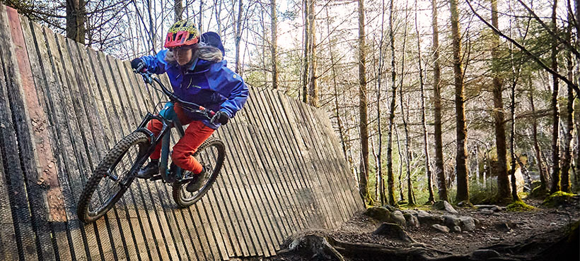 Student Tiandra scaling a wooden wall on a mountain bike