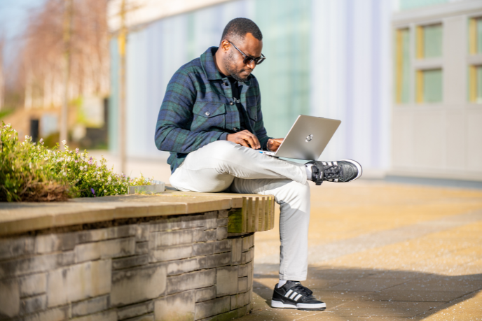 Student outside working at a laptop